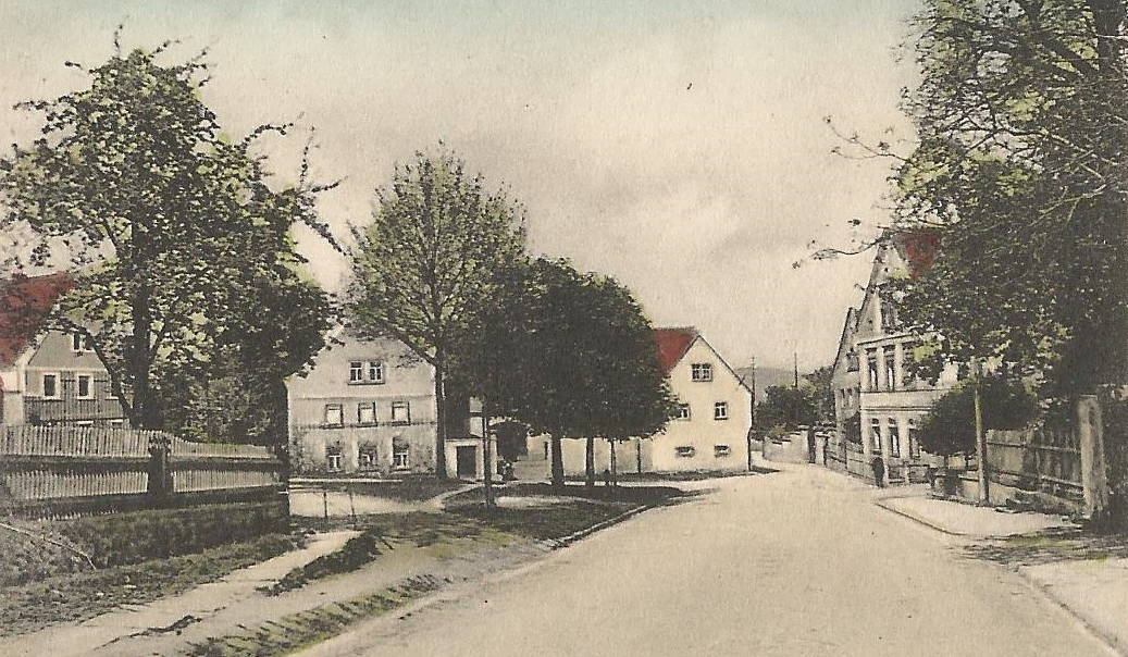 Bild vergrößern: Kolorierte Bildseite einer Ansichtskarte, Motiv: Lugturmstraße im Bereich des Dorfplatzes in nördliche Richtung, ca. 1910/15, Fotograf: unbekannt